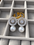 Silver-tone floral earrings featuring sparkling clear crystals and large lustrous white pearl drops, displayed in a soft gray jewelry box.