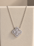 A silver-tone floral pendant necklace with clear stones, displayed on a beige jewelry bust.