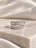 Adjustable silver-tone ring featuring a wide band of sparkling clear baguette-cut crystals with smaller round crystal accents, displayed on a cream marble surface.