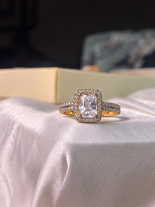 Gold-plated Xuping statement ring with a large rectangular clear center stone, surrounded by sparkling crystals and set on a double crystal-accented band.