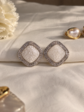 Ivory square stud earrings with a textured pearl-like center, surrounded by sparkling clear crystals and a polished silver-tone border.