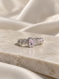 Adjustable silver-tone ring featuring a large blush-pink oval crystal surrounded by sparkling clear stones, with an intricate textured band.